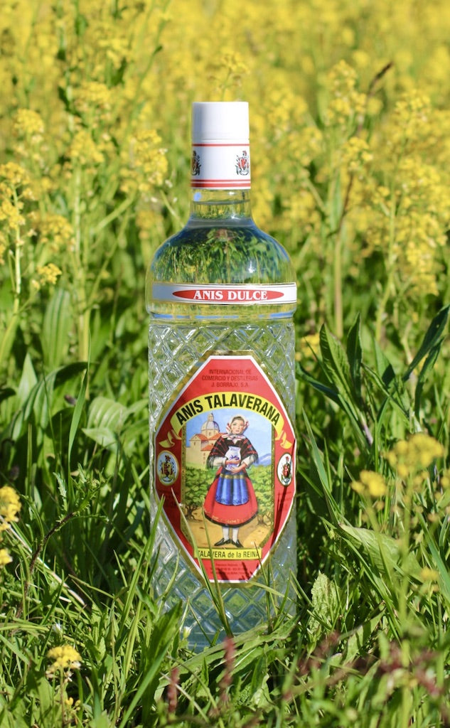 Anis Dulce Talaverana Anislikör Flasche im Gras mit gelben Blüten