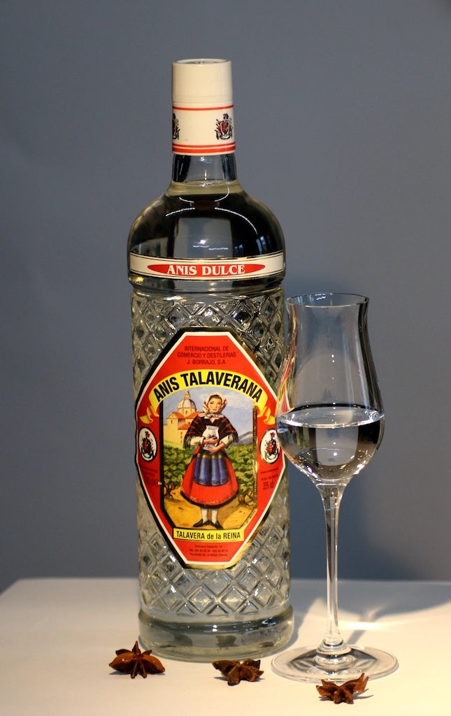 Anis Dulce Talaverana Anislikör Flasche neben Glas und Sternanis auf hellem Tisch