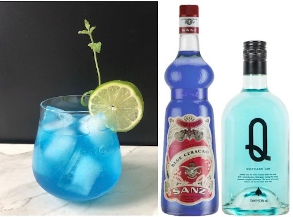 Blauer Blue Gin Blues Cocktail mit Limettenscheibe, daneben Blue Curacao Sirup von Sanz und Blue Gin „Q“ Flasche.