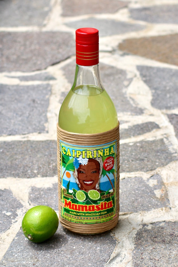 Mamasita Caipirinha Mix Flasche mit Limette auf Steinboden vor hellem Hintergrund