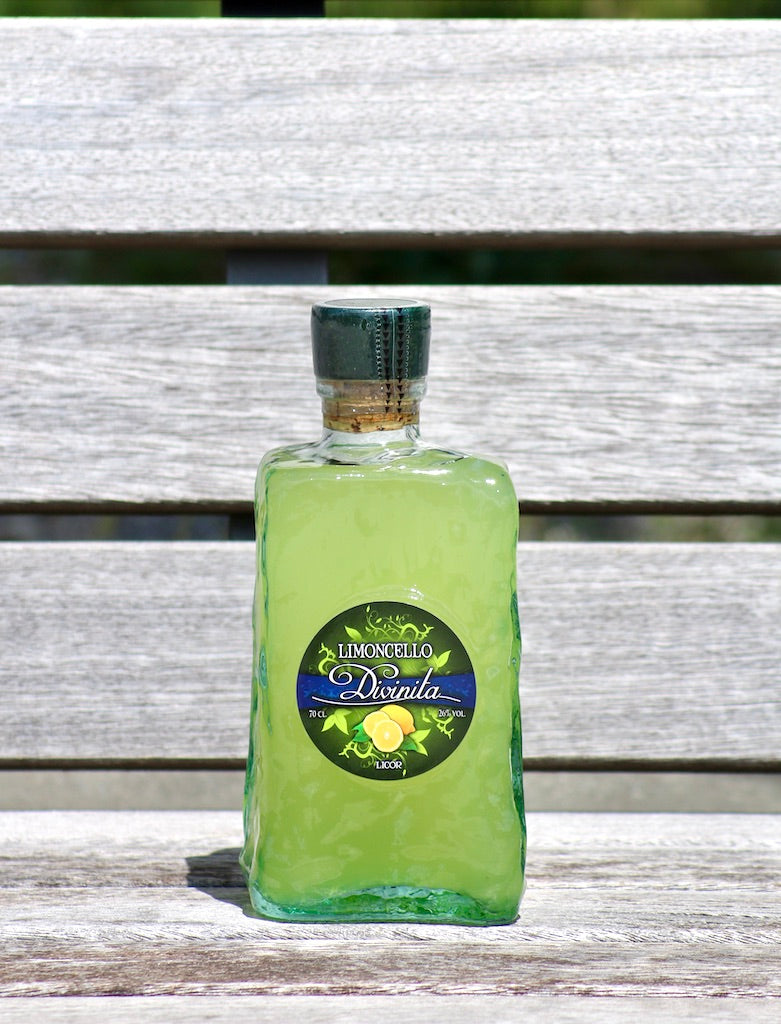 Limoncello Divinita Frasca Flasche auf heller Holzbank mit rundem Zitronenetikett und grünem Verschluss