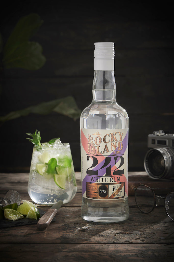 Rocky Island 242 White Rum Flasche neben Mojito mit Limette und Minze auf Holztisch