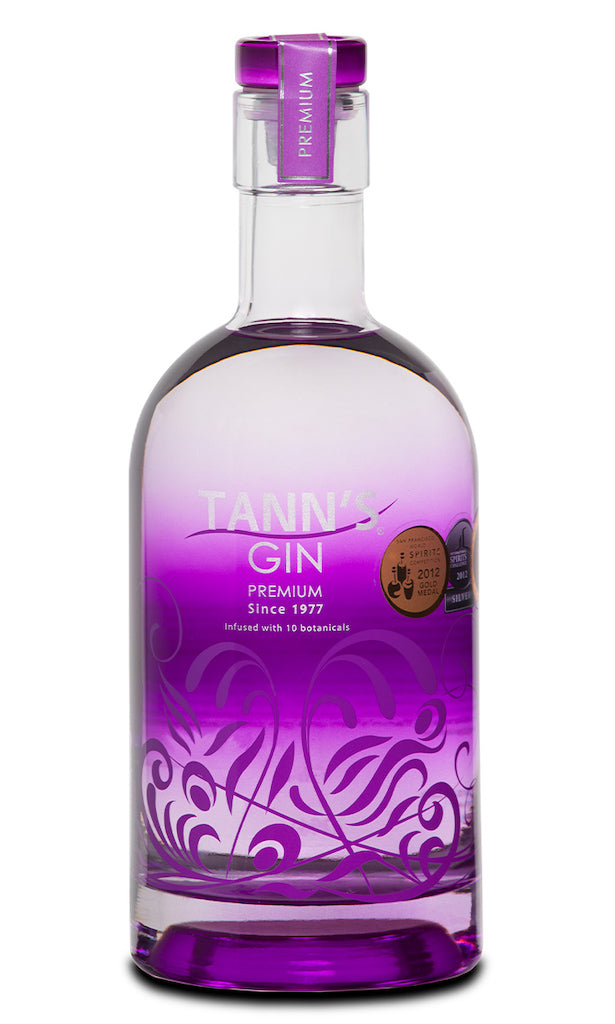 Tann’s Premium Gin in transparenter Flasche mit violettem Design, silberner Verzierung und violettem Verschluss.