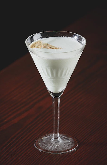 Alexander’s Mother Cocktail im Martini-Glas mit cremiger weißer Oberfläche auf dunklem Holztisch
