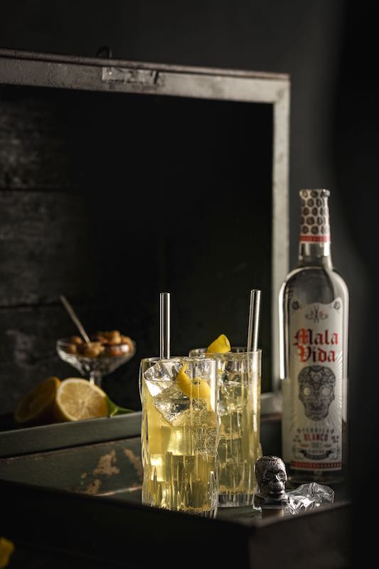 Buenos Noches Cocktail mit Tequila Mala Vida, serviert auf Eis mit Zitronenzeste im Highball-Glas.