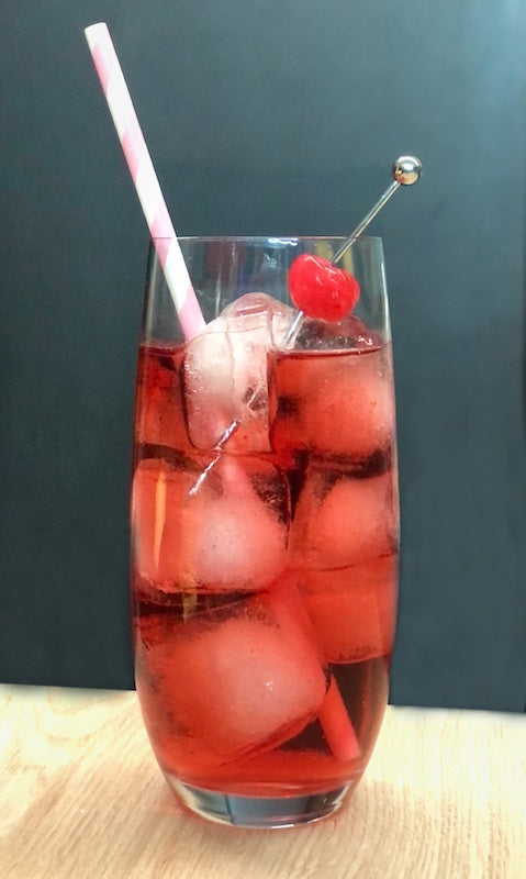 Canadian Princess Cocktail im Highball-Glas mit Eis, Strohhalm und Cocktailkirsche vor dunklem Hintergrund