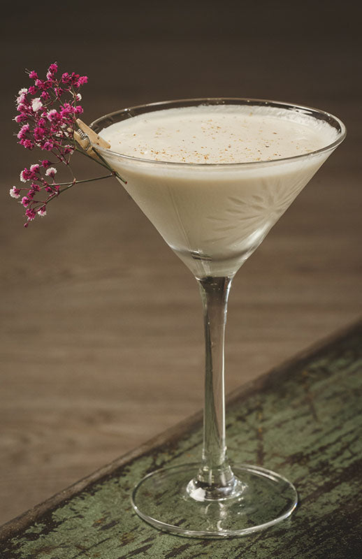  French Royal Andrew Cocktail im Martiniglas, garniert mit rosa Blütenzweig und Zimtstange am Glasrand