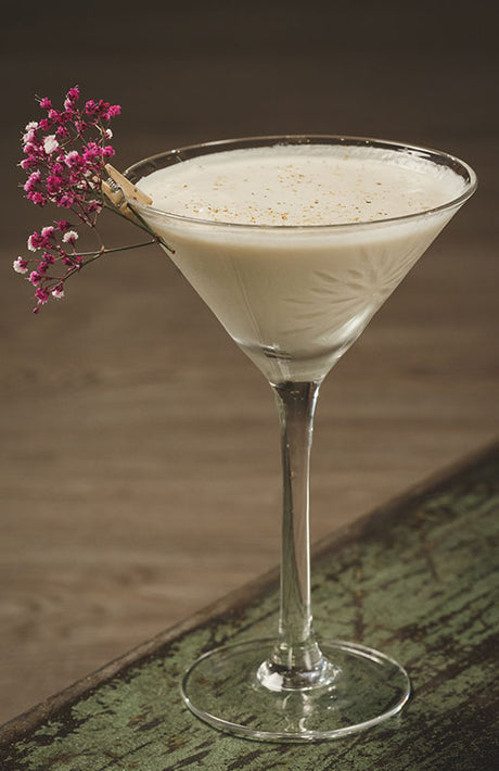  French Royal Andrew Cocktail im Martiniglas, garniert mit rosa Blütenzweig und Zimtstange am Glasrand
