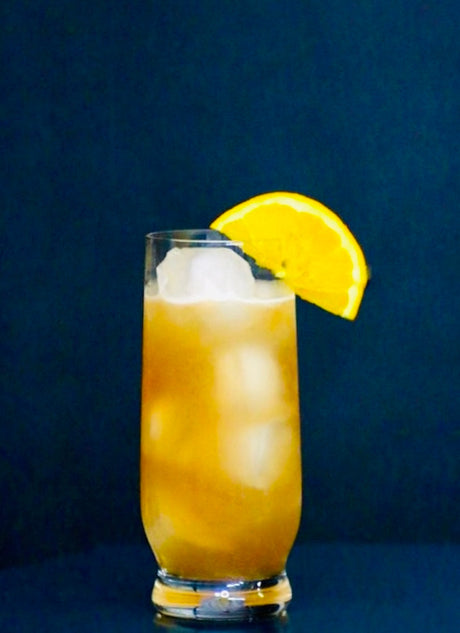 Alkoholfreier Georgia Peach Cocktail in einem Highball-Glas mit Eiswürfeln und Orangenscheibe als Dekoration.