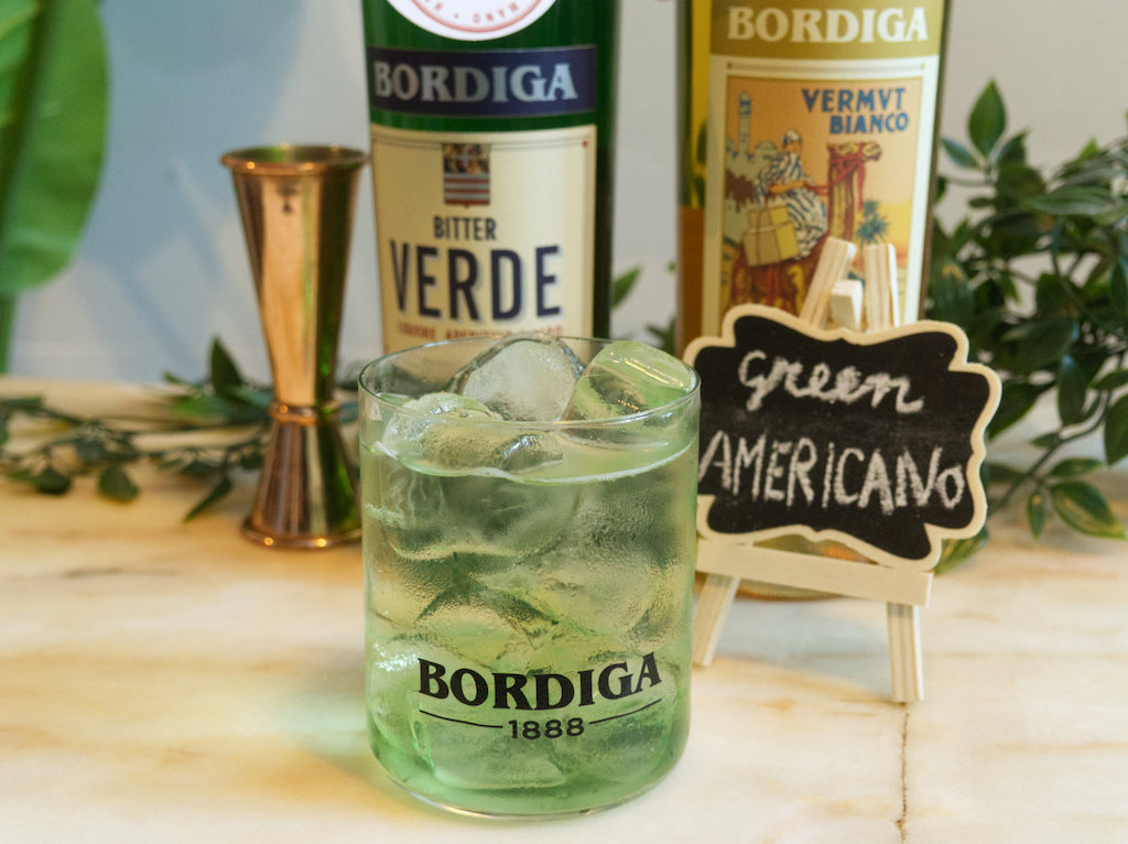 Green Americano Cocktail mit Eis im Bordiga-Glas, dahinter Bitter Verde und Vermouth Bianco von Bordiga