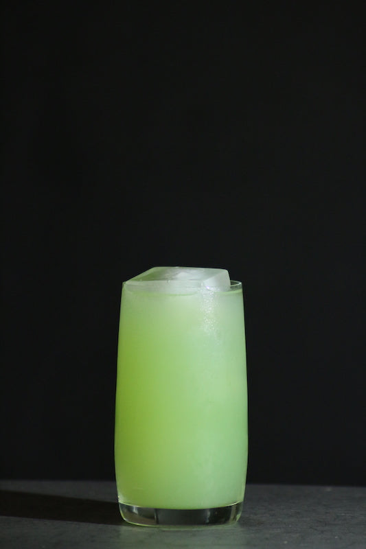 Perroquet Cocktail im Collins Glas, hellgrün mit Eiswürfeln auf dunklem Untergrund