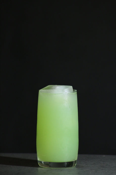 Perroquet Cocktail im Collins Glas, hellgrün mit Eiswürfeln auf dunklem Untergrund