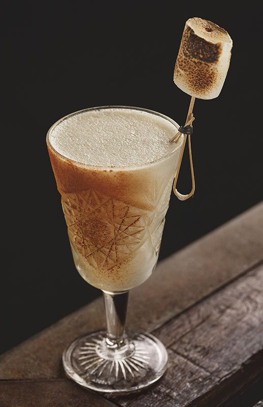 Napolitan Vodka Fizz Cocktail im Glas mit Schaum und geröstetem Marshmallow als Garnitur am Glasrand