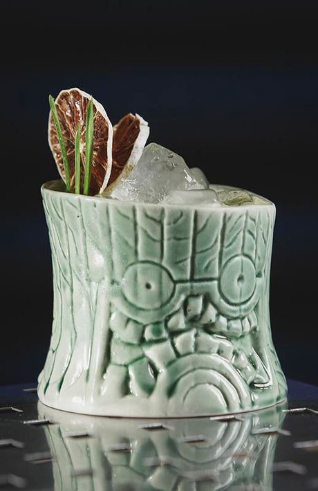 No Punch alkoholfreier Cocktail auf Eis in einem grünen Tiki-Becher mit Muster, garniert mit getrockneten Zitrusscheiben und Kräutern.