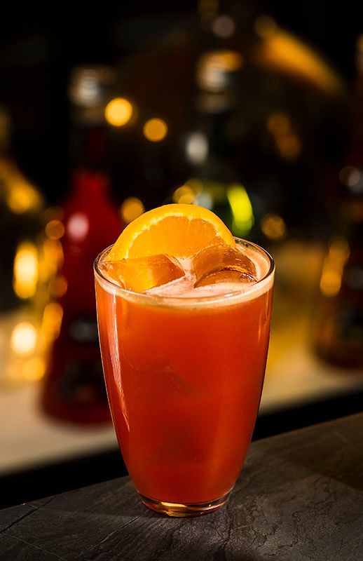 Orgeat Madras Cocktail im Highballglas mit Eis, Orange und roter Cocktailfarbe