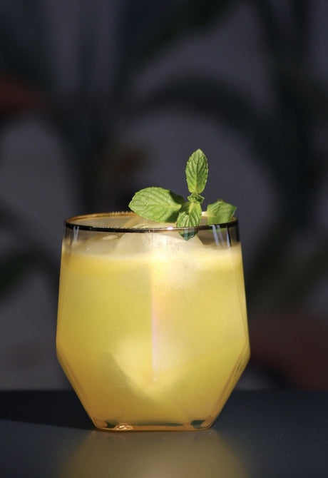 Potted Parrot Cocktail im Whiskeyglas, goldgelb, mit frischer Minze auf dunklem Untergrund