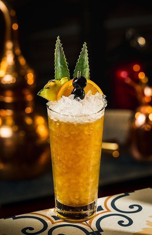 Wermut Ananas Cobbler Cocktail im Highball-Glas mit Crushed Ice, Ananas, Orange und Kirsche dekoriert