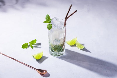 Whitestrand Spiced Rum Mojito Cocktail im Highball-Glas, garniert mit frischer Minze und Limetten auf einem hellen Tisch.