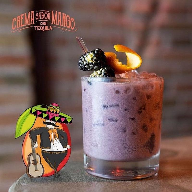 Wild Mariachi el Mango cremiger Cocktail im Glas mit Eis, Brombeeren und Orangenschale