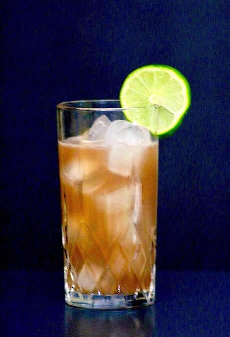 Alkoholfreier Woo Woo Cocktail in einem Glas mit Eiswürfeln und einer Limettenscheibe als Dekoration.