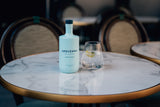 Arduenna No Alcohol 0,5 l mit Glas Tonic, Eis, Zitrone und Thymian auf rundem Marmortisch mit Bistrostuhl im Hintergrund
