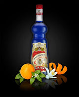 Flasche Blue Curaçao Sirup von Sanz mit Orange, Blüte und Schale vor schwarzem Hintergrund.