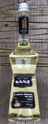 Flasche Sanz geräucherter Rohrzuckersirup auf rustikalem Holzbrett, mit schwarzem Etikett und stilvollem Design.