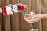 The Goat Strawberry Gin wird in ein Glas mit Eiswürfeln und Limettenscheiben für einen erfrischenden Gin & Tonic gegossen.