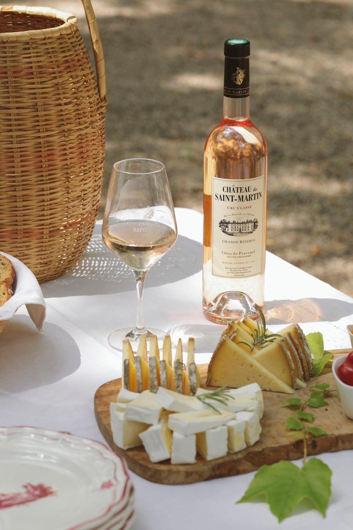 Château de Saint Martin Grande Réserve Rosé mit Glas und Käseplatte auf gedecktem Tisch im Freien.