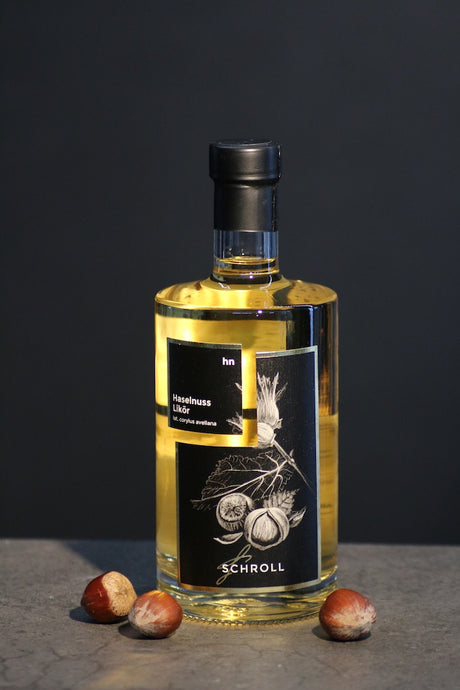 Haselnuss Likör Schroll Flasche mit Haselnüssen auf dunklem Hintergrund