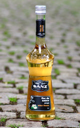 Holunderblütensirup Sanz 0,7L auf Kopfsteinpflaster mit natürlichem Licht und grünem Moos zwischen den Steinen.