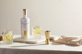 Salcombe Island Street Rumflasche mit zwei Tumblern, Limettenscheiben und Barmaß auf heller Tischfläche.