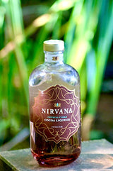 Nirvana Crystal Clear Kakaolikör in transparenter Glasflasche mit braunem Etikett vor grünem Hintergrund