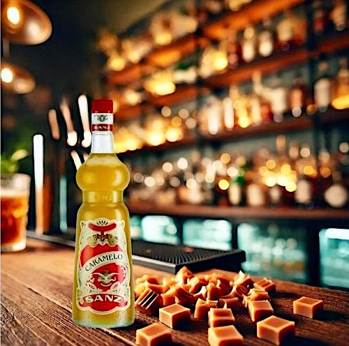 Karamell-Sirup Sanz 1L auf einer Bar mit Karamellstückchen im Vordergrund und beleuchteten Flaschen im Hintergrund.