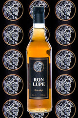 Rum Añejo Lupe, goldbraune Flasche mit schwarzem Etikett, vor dekorativem Hintergrund mit wiederholtem Logo der Marke.