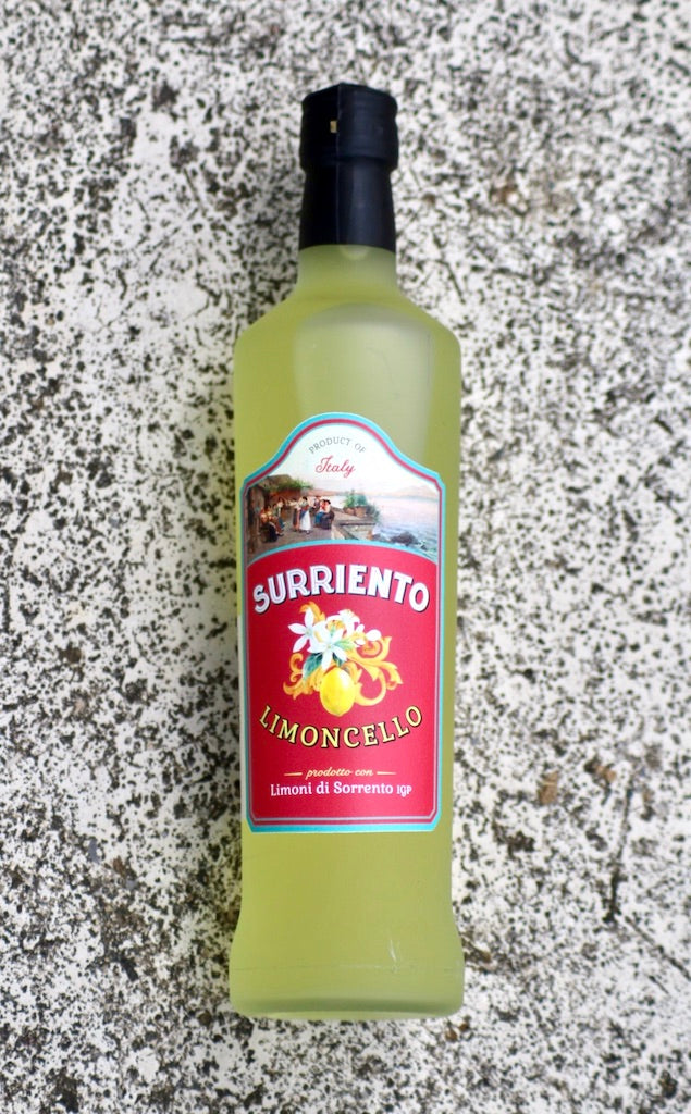 Flasche Surriento Limoncello mit rotem Etikett, liegend auf heller, gesprenkelter Steinoberfläche.