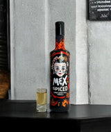 Mex Spiced Spirituose mit Tequila und Chili in schwarzer Flasche, daneben Shotglas mit Mex Spiced