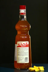 Mango Sirup Sanz 1L Flasche, Rückseite mit Etikett und Zutatenliste, daneben frische Mangostücke auf einem Spieß.