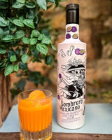 Flasche Sombrero Mexicano Maracuja-Tequila-Likör mit Totenkopf-Design, dekoriert mit Passionsfrüchten, neben einem Glas mit Eis.