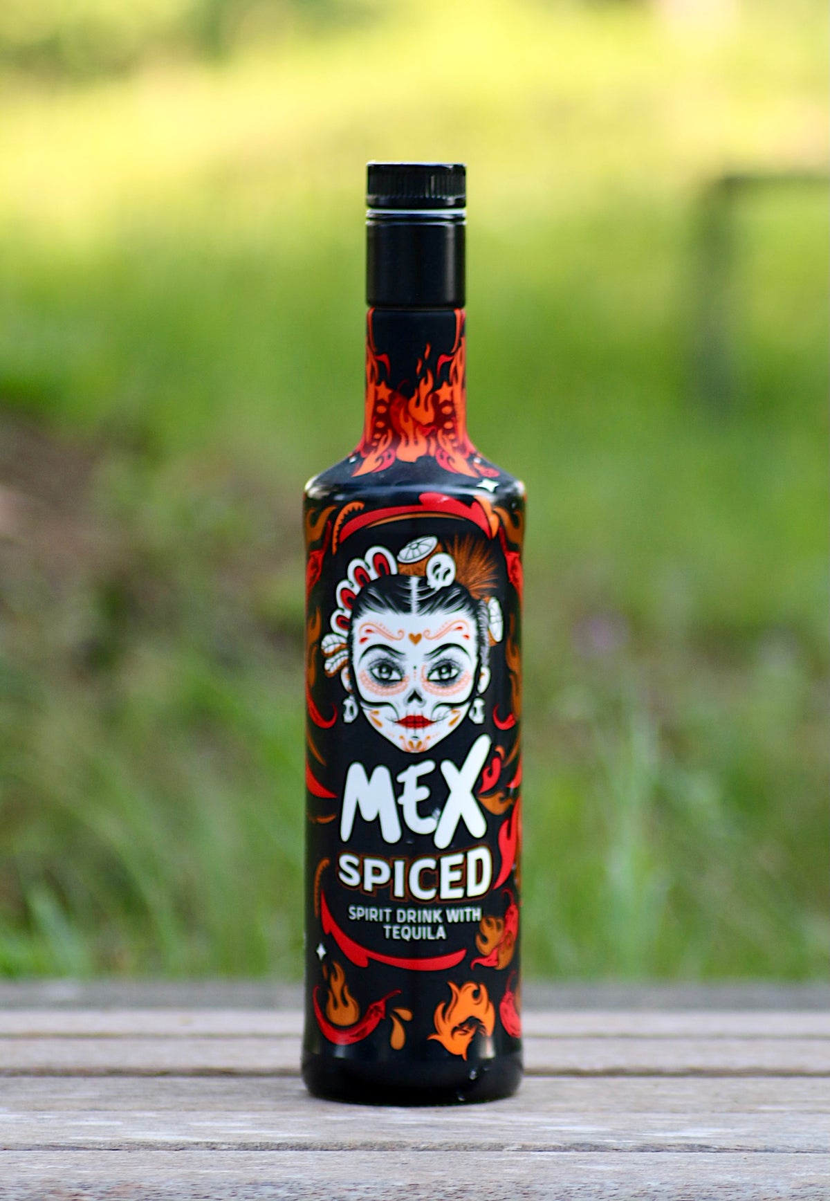 Alttext: Mex Spiced Tequila Spirituose mit Chili, Flasche mit feurigem Design und mexikanischem Totenkopf-Motiv.