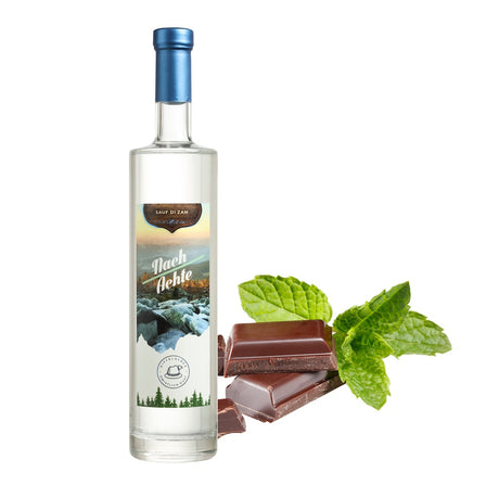 Flasche 'Nach Achte' Gipfelglück Likör mit blauem Verschluss, arrangiert neben Zartbitterschokolade und frischen Minzblättern vor weißem Hintergrund.