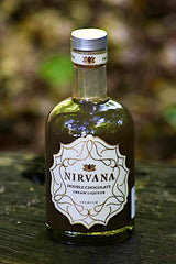 Flasche Nirvana Double Chocolate Cream Liqueur, mit edlem Etikett und dunkler Schokoladenfarbe, auf einem Holztisch vor einem unscharfen, natürlichen Hintergrund.