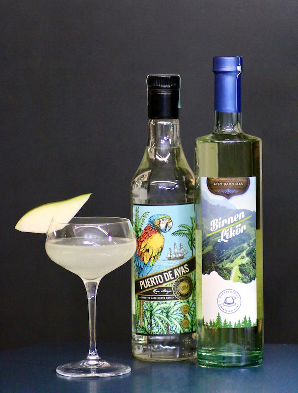Pear Daiquiri im Coupette-Glas mit Birnenscheibe, daneben eine Flasche Puerto de Ayas Rum und Birnenlikör Gipfelglück.
