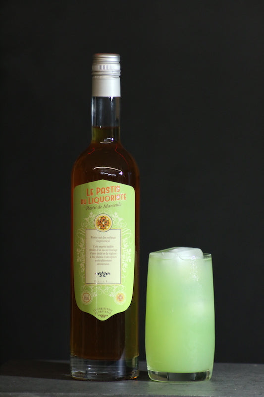 Perroquet Cocktail hellgrün im Glas neben Le Pastis du Liquoriste Flasche auf dunklem Untergrund