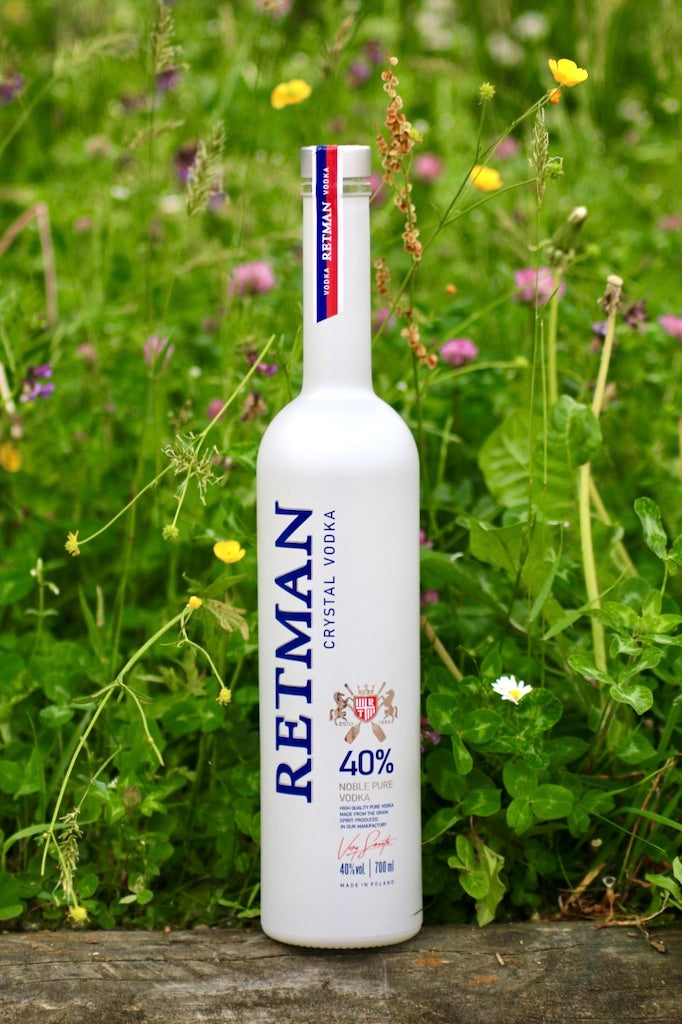 Retman Crystal Vodka Flasche auf Wiese mit grünen Pflanzen und kleinen Blüten