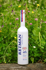 Retman Crystal Vodka Flasche auf Wiese mit grünen Pflanzen und kleinen Blüten