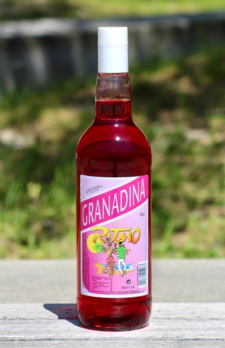 Flasche Ritmo Granadina ohne Zucker, 1 L, mit pinkfarbenem Etikett und tropischem Tanzmotiv, roter Sirup, weißer Schraubverschluss.