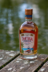 Tartuga Rumflasche auf verwittertem Holzbrett mit See im Hintergrund und maritimem Etikett