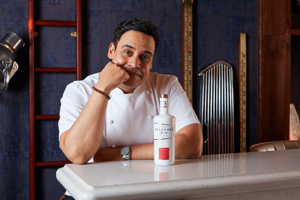 Paul Ainsworth, Michelin-Sternekoch, sitzt an einer Theke neben einer Flasche Salcombe Gin Daring, Limited Edition.