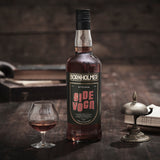 Bornholmer Sidevogn Bitter Dram 70cl, brauner Schnaps in Glasflasche mit Vintage-Design, serviert in einem Cognacglas auf Holz.